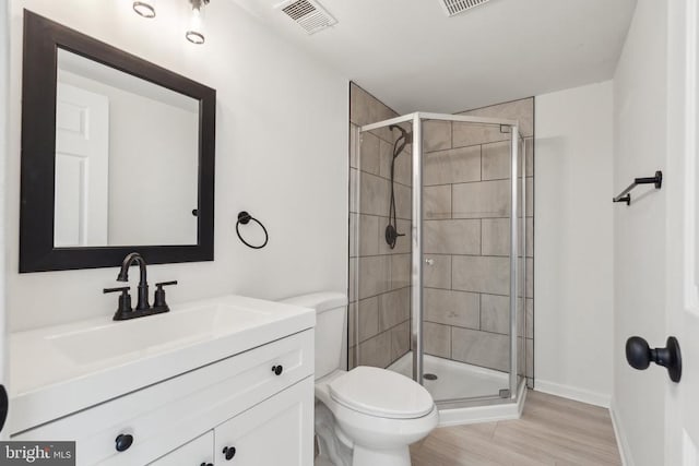 bathroom featuring a shower stall, wood finished floors, toilet, and baseboards