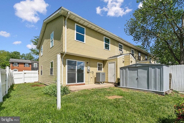 rear view of house with central AC unit, a storage shed, a patio area, and an outbuilding