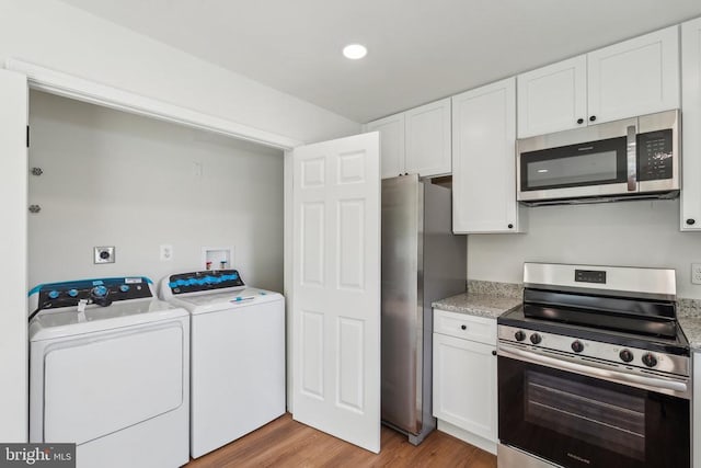 kitchen with stainless steel appliances, washing machine and dryer, light wood-style floors, white cabinetry, and recessed lighting