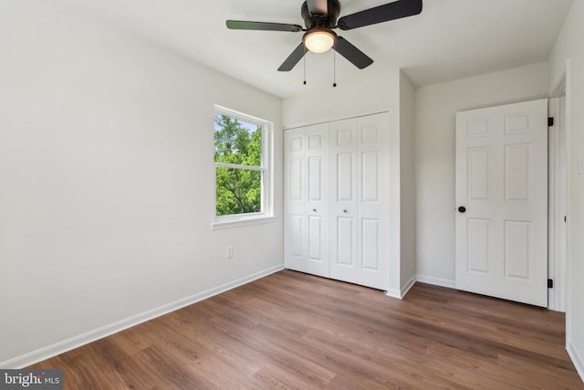 unfurnished bedroom with baseboards, wood finished floors, and a closet
