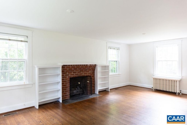 2201 Stadium Rd, Charlottesville, VA 22903 - unfurnished living room featuring wood finished floors, radiator, a brick fireplace, and healthy amount of natural light