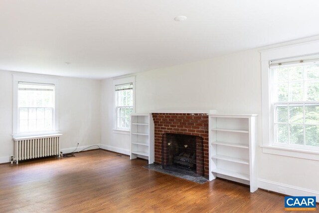 2201 Stadium Rd, Charlottesville, VA 22903 - unfurnished living room with radiator heating unit, wood finished floors, and a brick fireplace