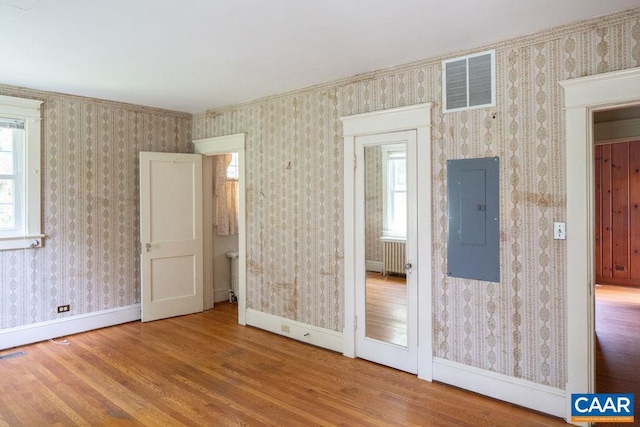 2201 Stadium Rd, Charlottesville, VA 22903 - unfurnished bedroom featuring wood finished floors, electric panel, wallpapered walls, and radiator