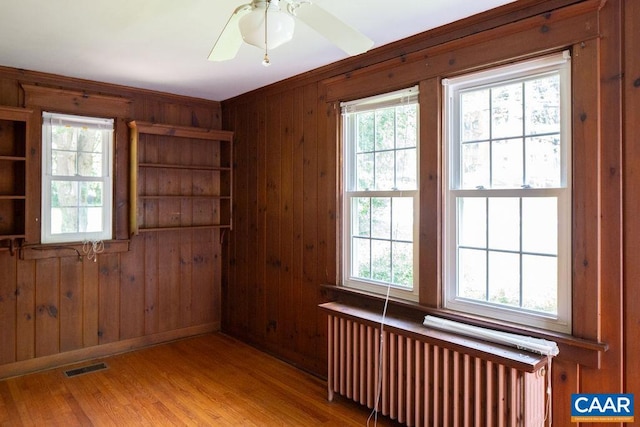 2201 Stadium Rd, Charlottesville, VA 22903 - empty room with radiator heating unit, wooden walls, a ceiling fan, and wood finished floors