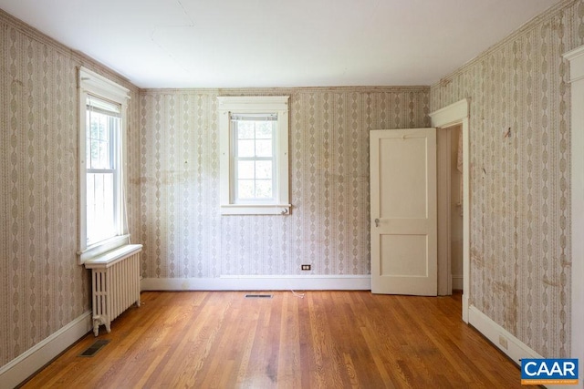 2201 Stadium Rd, Charlottesville, VA 22903 - empty room with wood finished floors, healthy amount of natural light, radiator, and wallpapered walls