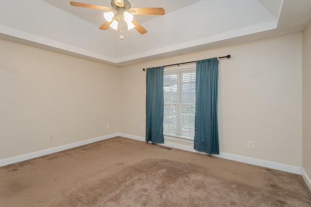 empty room featuring ceiling fan, carpet flooring, and a tray ceiling