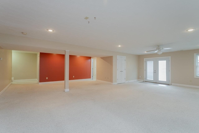 basement with french doors, light colored carpet, and ceiling fan