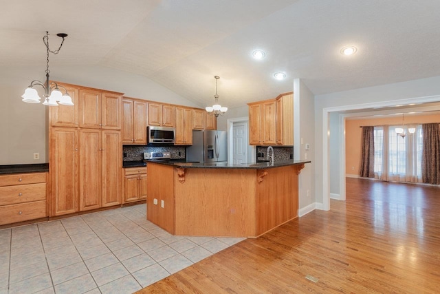 kitchen featuring appliances with stainless steel finishes, a breakfast bar area, pendant lighting, and an inviting chandelier