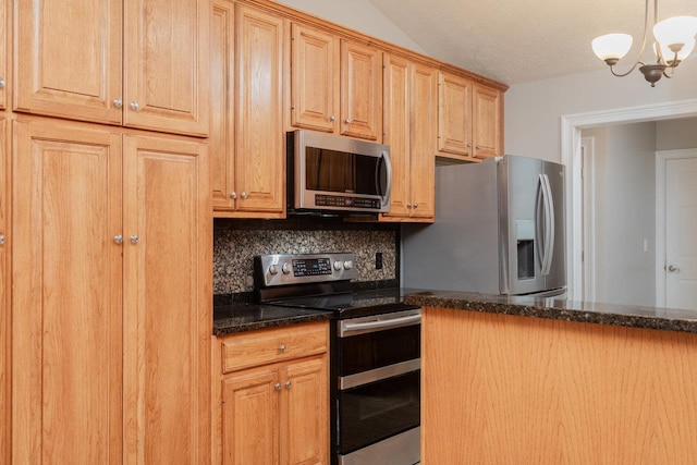 kitchen with appliances with stainless steel finishes, dark stone countertops, hanging light fixtures, a textured ceiling, and decorative backsplash