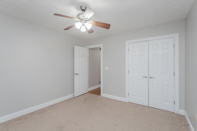 unfurnished bedroom featuring ceiling fan, light colored carpet, a closet, and a textured ceiling