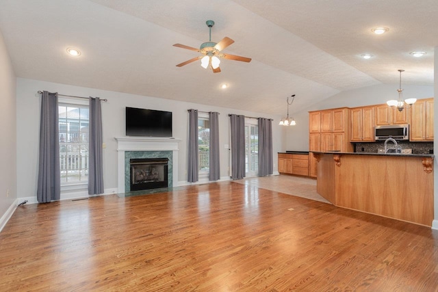 kitchen with a high end fireplace, light hardwood / wood-style floors, and hanging light fixtures