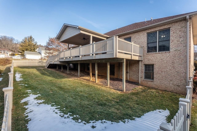 snow covered back of property with a yard, ceiling fan, and a deck