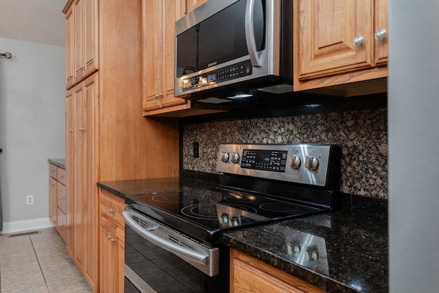 kitchen with tasteful backsplash, stainless steel appliances, light tile patterned floors, and dark stone countertops