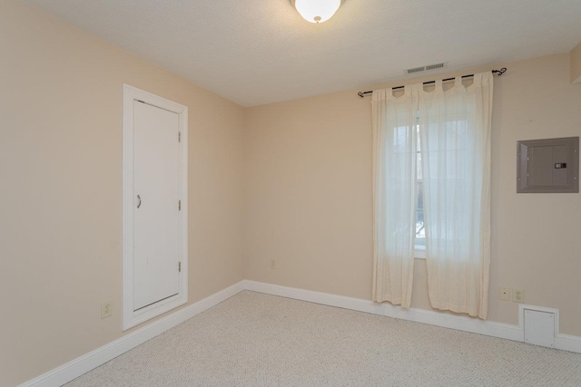 empty room with carpet floors, electric panel, and a textured ceiling