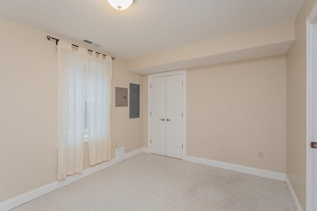 carpeted spare room with electric panel and a textured ceiling