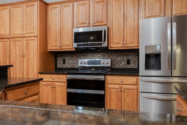 kitchen featuring tasteful backsplash, appliances with stainless steel finishes, and dark stone counters