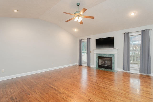 unfurnished living room featuring vaulted ceiling, plenty of natural light, a fireplace, and light hardwood / wood-style flooring