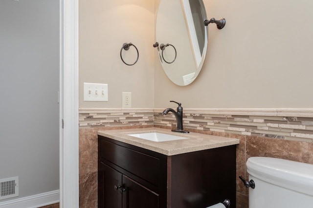 bathroom with vanity, toilet, and tile walls