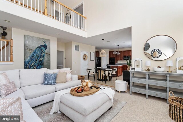 living area with a towering ceiling and light carpet