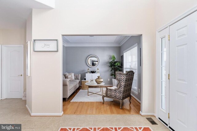tiled foyer featuring baseboards and crown molding
