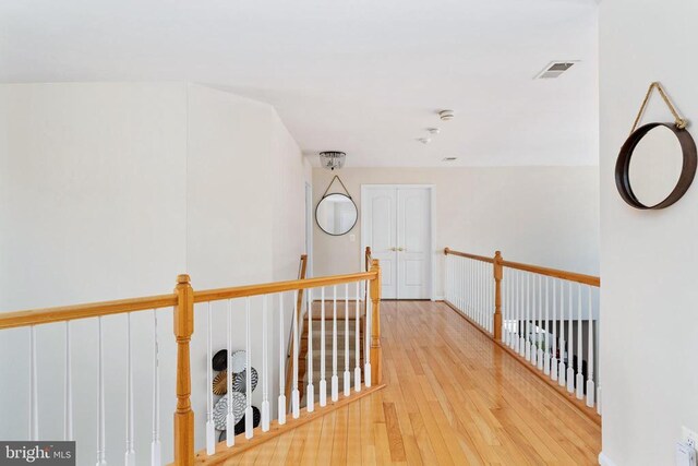 corridor with wood finished floors and an upstairs landing