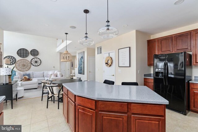 kitchen with black fridge, a kitchen island, decorative light fixtures, light tile patterned floors, and open floor plan
