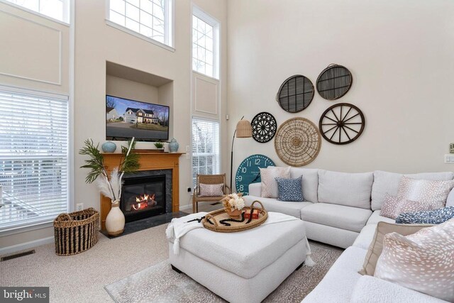living area with a fireplace with flush hearth, carpet flooring, and a towering ceiling