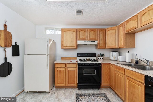 kitchen with freestanding refrigerator, gas range, under cabinet range hood, a sink, and black dishwasher