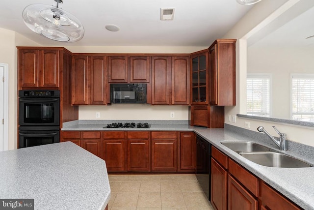 kitchen with black appliances, a sink, glass insert cabinets, light tile patterned floors, and light countertops