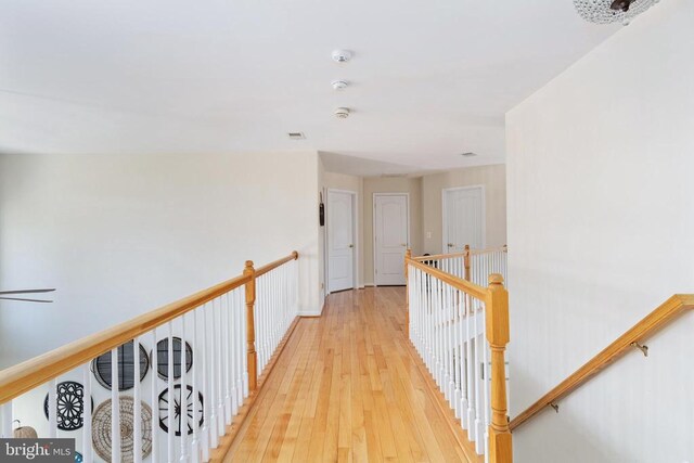 hallway with light wood-style floors and an upstairs landing
