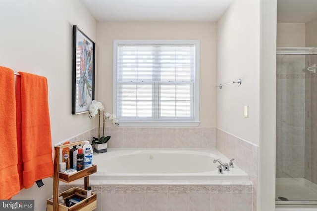 bathroom featuring a shower stall and a bath