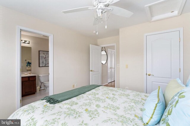 bedroom with ensuite bath, attic access, light wood-type flooring, and ceiling fan