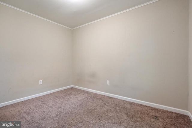 carpeted empty room featuring crown molding and baseboards