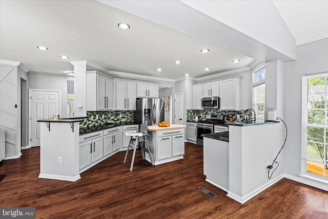 6915 Yeoman Ct, Fredericksburg, VA 22407 - kitchen with appliances with stainless steel finishes, crown molding, decorative backsplash, a kitchen breakfast bar, and a peninsula