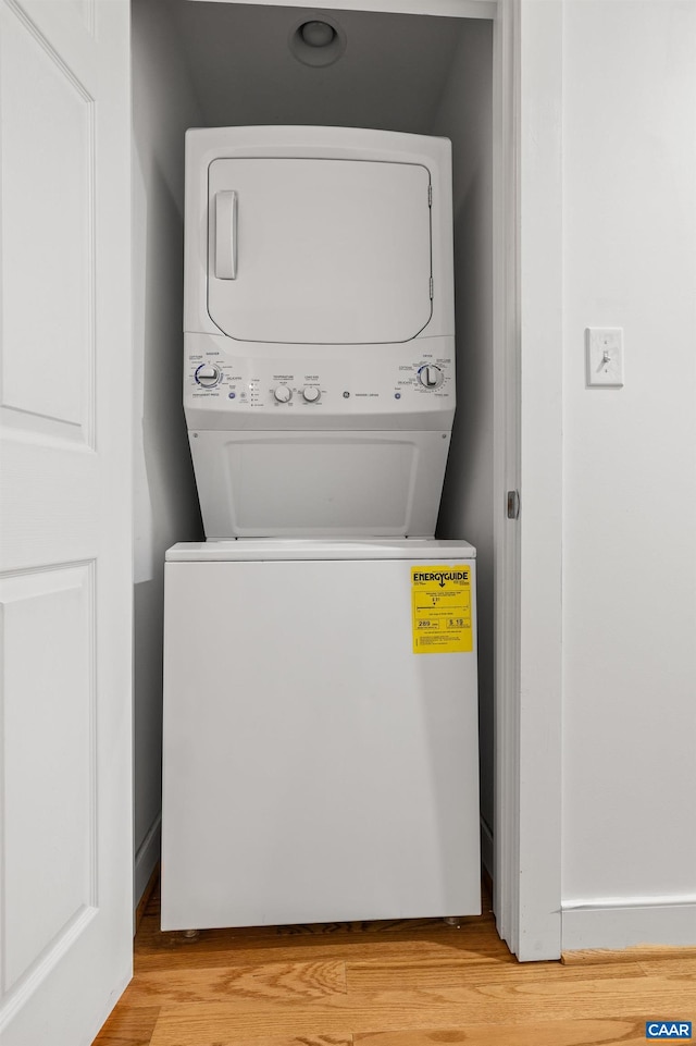 clothes washing area featuring light wood-type flooring, laundry area, and stacked washer and clothes dryer