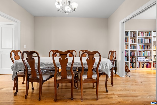 dining area with light wood-style flooring and a notable chandelier