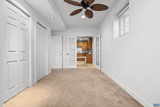 unfurnished bedroom with french doors, recessed lighting, baseboards, light carpet, and multiple closets
