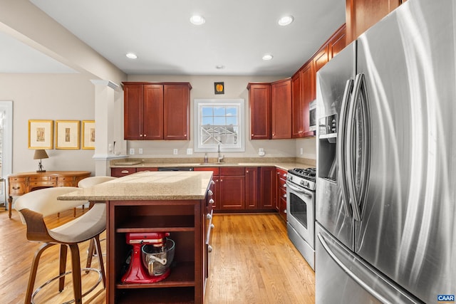 kitchen with a breakfast bar, light wood finished floors, a sink, a kitchen island, and stainless steel appliances
