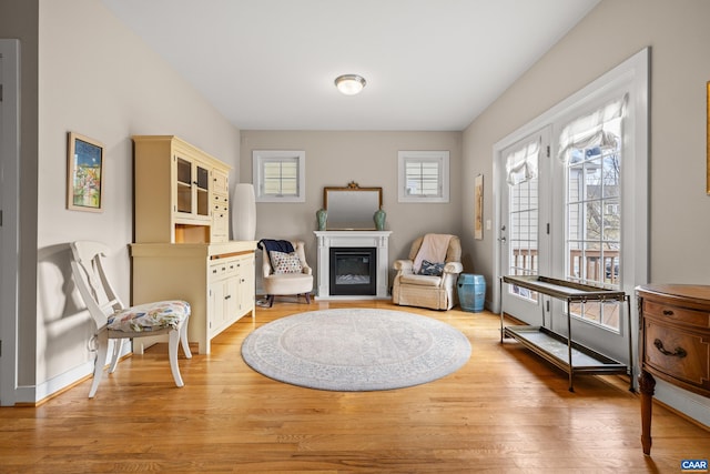 sitting room with light wood-type flooring and a glass covered fireplace
