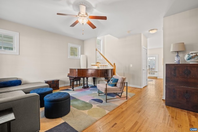 living room featuring a wealth of natural light, light wood-type flooring, baseboards, and a ceiling fan