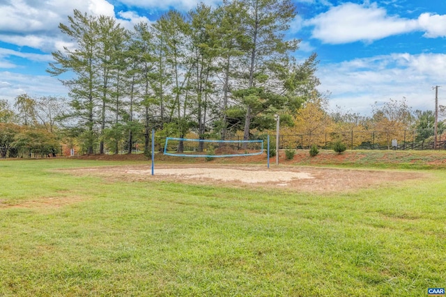 view of community featuring a yard, fence, and volleyball court