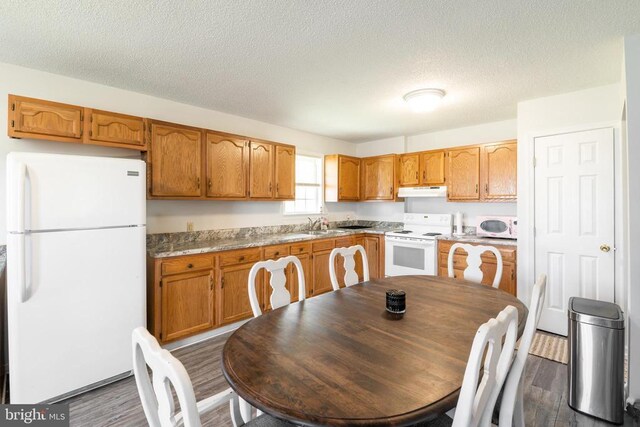 301 Charles St, Gordonsville, VA 22942 - kitchen with white appliances, dark wood-style flooring, a textured ceiling, under cabinet range hood, and brown cabinets