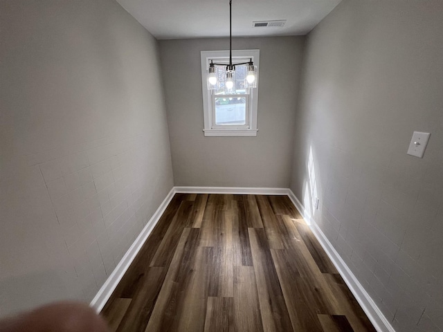 unfurnished dining area with dark wood finished floors, baseboards, and a chandelier