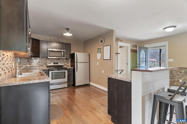 1481 Red Bird Dr, Stanardsville, VA 22973 - kitchen featuring a breakfast bar area, dark brown cabinets, light wood-style flooring, a sink, and appliances with stainless steel finishes