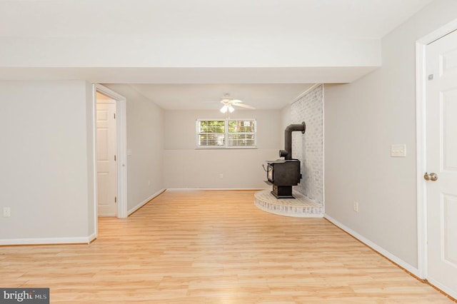 7001 Aspen Ln, Spotsylvania, VA 22551 - unfurnished living room featuring a wood stove, light wood-style floors, a ceiling fan, and baseboards