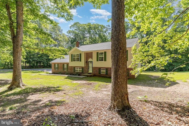 7001 Aspen Ln, Spotsylvania, VA 22551 - split foyer home with a chimney, a front yard, brick siding, and view of scattered trees