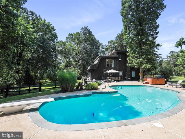  - swimming pool featuring a hot tub, a patio, a diving board, and view of wooded area