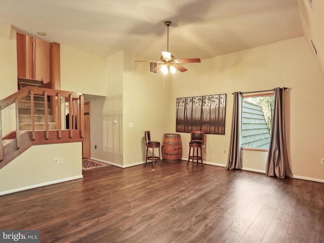  - unfurnished living room with ceiling fan, high vaulted ceiling, wood finished floors, and stairs