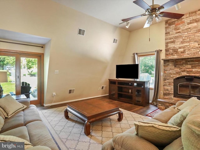  - living room featuring wood finished floors, healthy amount of natural light, ceiling fan, a high ceiling, and a fireplace
