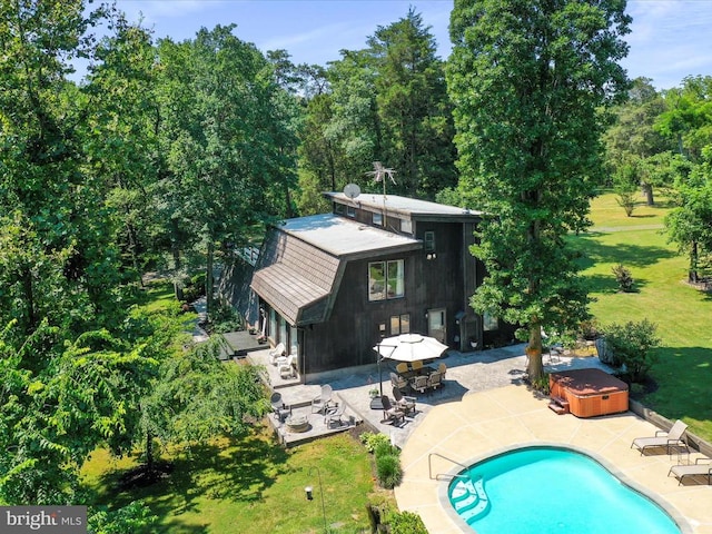  - rear view of property featuring a hot tub, a patio, an outdoor pool, and a lawn